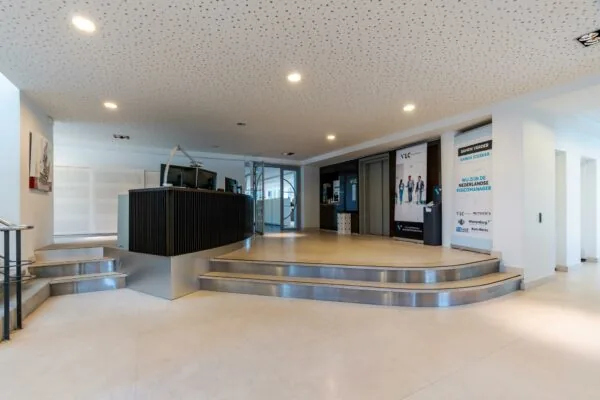 Moderne entreehal met ontvangstbalie en posters van VLC & Partners aan de Van Alkemadelaan.